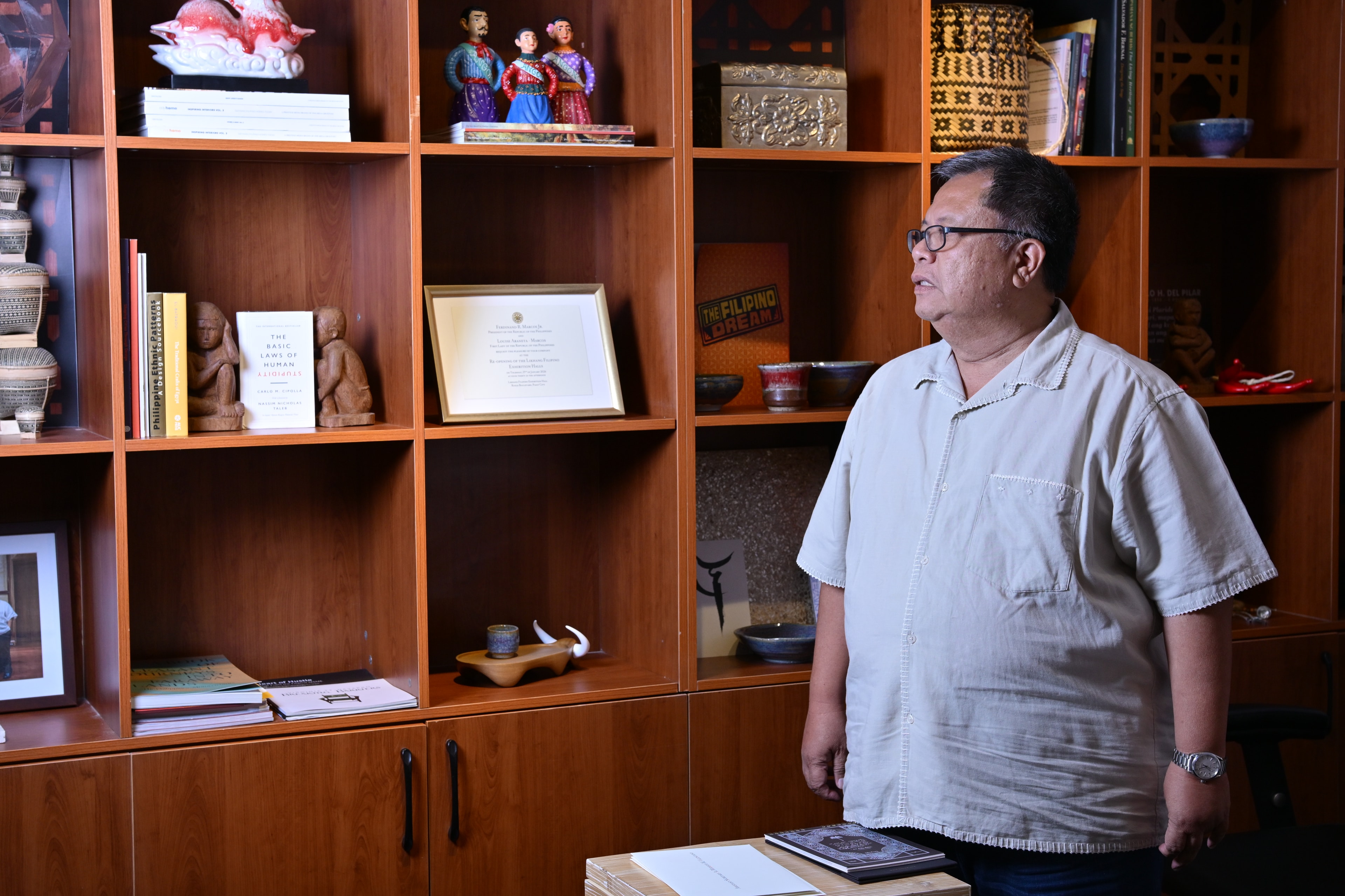 Al Valenciano photographed in profile against a bookshelf at the Likhang Filipino exhibit