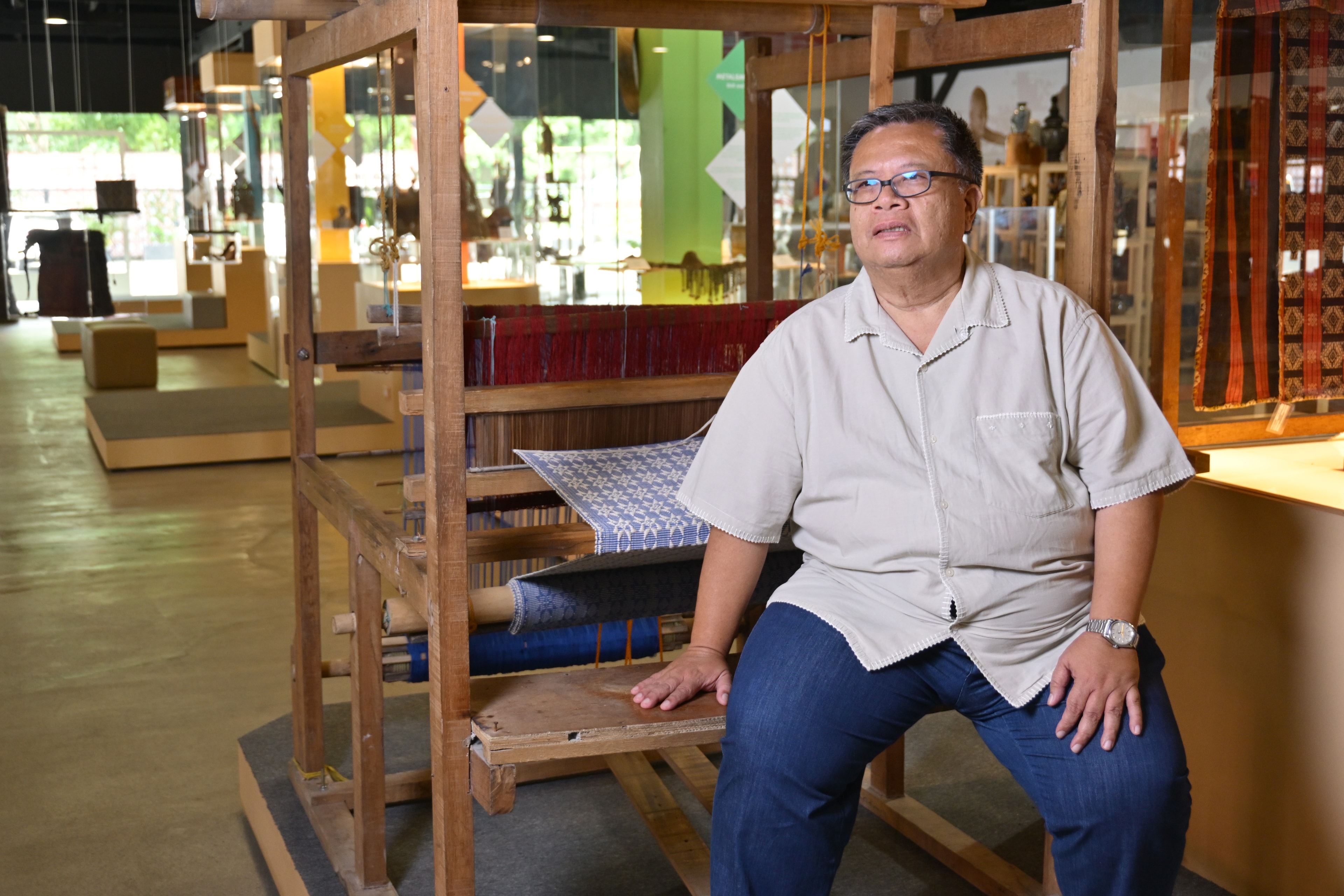 Al Valenciano seated at a loom in the exhibit hall